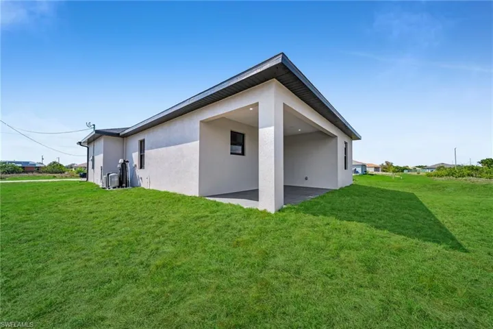 View of side of home with stucco siding, a lawn, and a patio