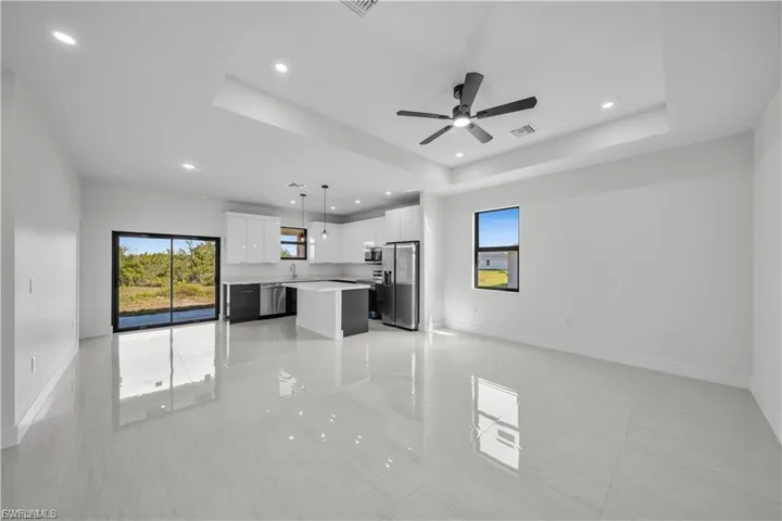 Unfurnished living room with a raised ceiling, recessed lighting, a ceiling fan, and light tile patterned flooring