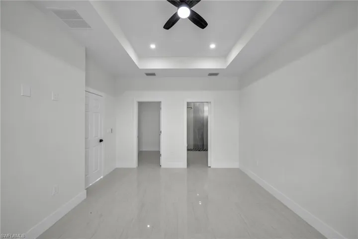 Unfurnished room featuring a raised ceiling, recessed lighting, and ceiling fan