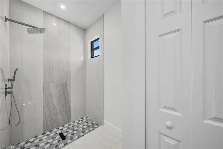 Bathroom with tiled shower, light tile patterned floors, and recessed lighting