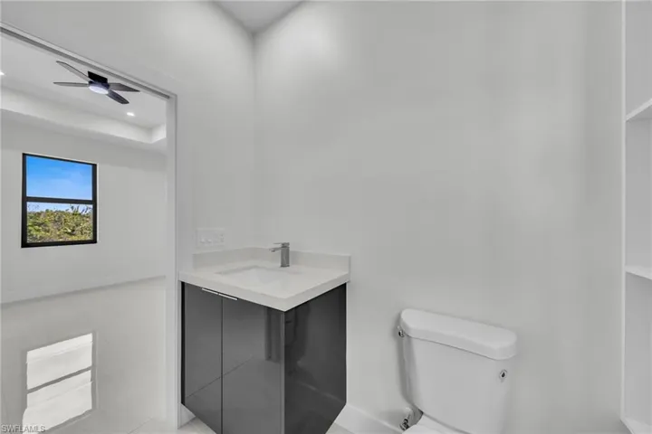 Half bath with vanity, light tile patterned floors, and ceiling fan
