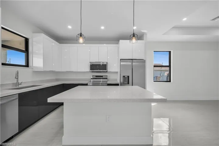 Kitchen featuring modern cabinets, white cabinets, stainless steel appliances, and recessed lighting