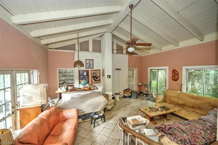 Tiled living room with ceiling fan, a wealth of natural light, and beamed ceiling