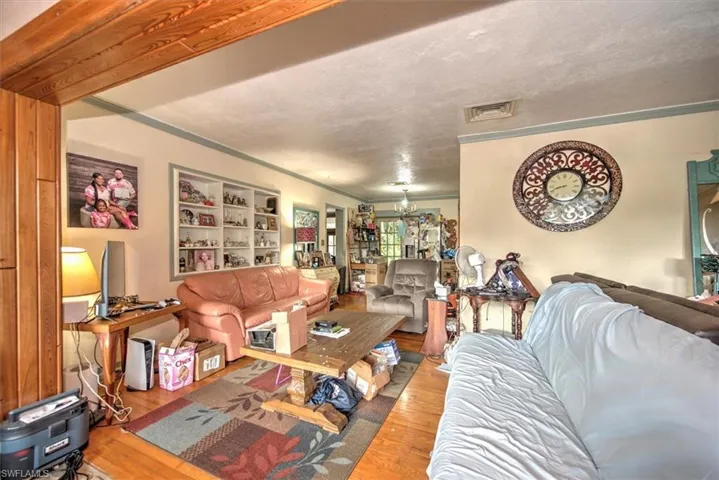 Living room featuring light wood-type flooring, ornamental molding, and a textured ceiling