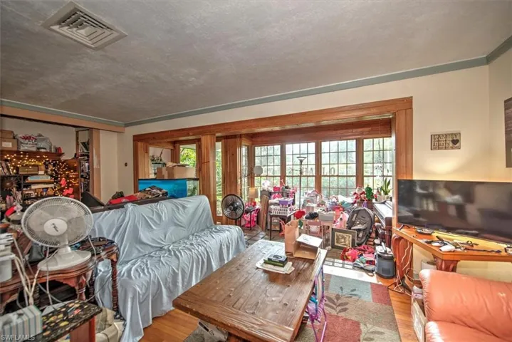 Living room featuring wood-type flooring, a textured ceiling, and ornamental molding
