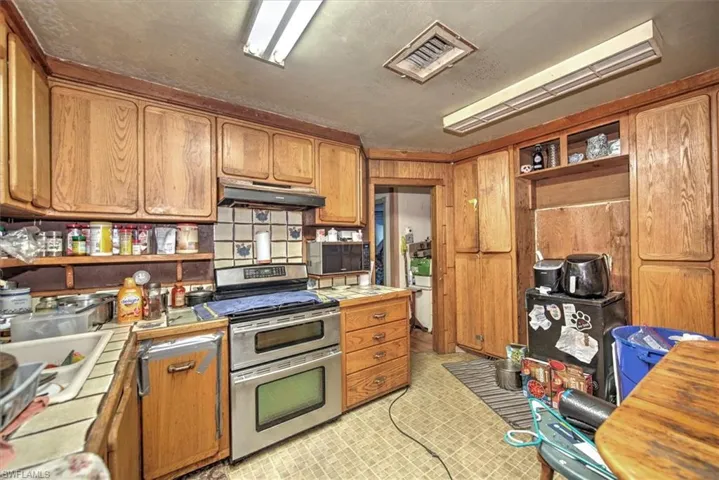 Kitchen featuring tile countertops, stainless steel range, and light tile patterned floors