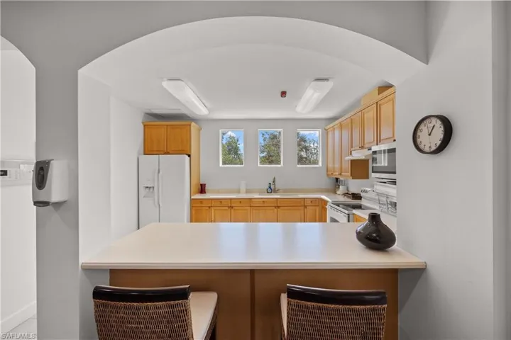 Kitchen featuring light brown cabinetry, sink, white appliances, and kitchen peninsula