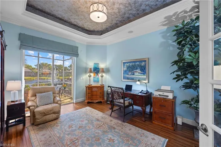 Home office with access to the back lanai, featuring crown molding, hardwood / wood-style floors, and a tray ceiling.