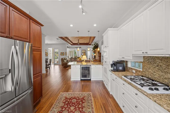 Kitchen featuring hanging light fixtures, beverage cooler, white cabinets, and kitchen peninsula