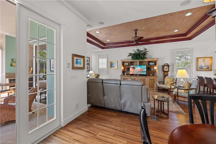 Living room with wood ceiling, light hardwood / wood-style flooring, ornamental molding, a raised ceiling, and ceiling fan