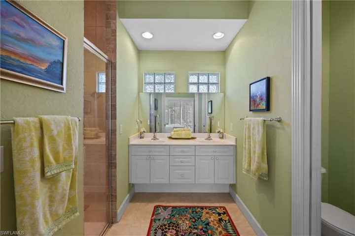 Cabana ensuite bathroom featuring tile patterned flooring, vanity, a shower with shower door, and toilet