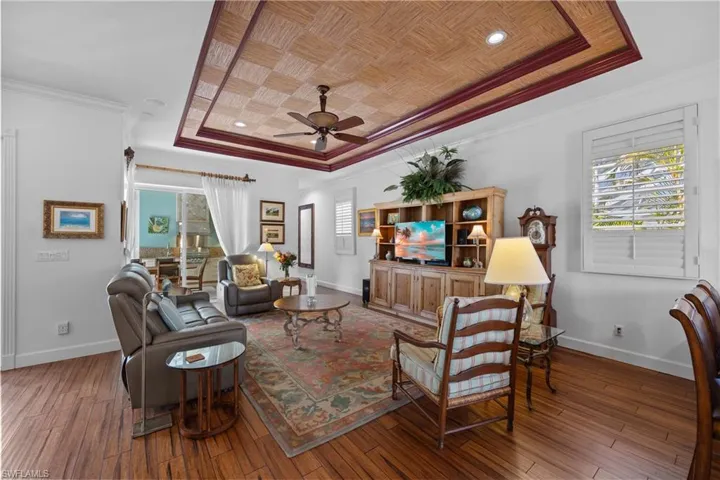 Living room featuring ceiling fan, hardwood / wood-style floors, ornamental molding, wooden ceiling, and a raised ceiling