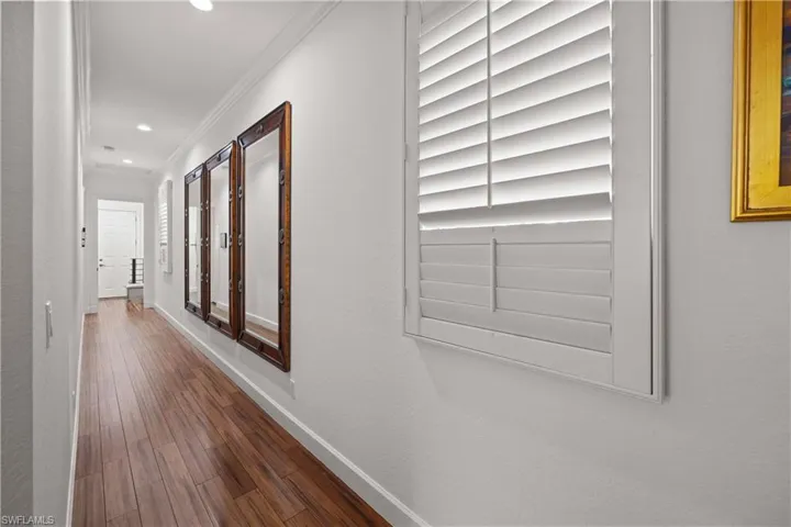 Gallery (long hallway) with ornamental molding and dark wood-type flooring
