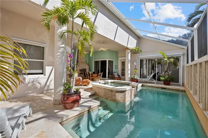 View of swimming pool featuring a lanai, ceiling fan, exterior fireplace, a patio area, and an in ground hot tub