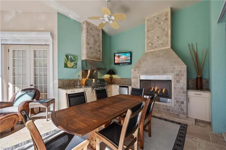 Dining room featuring vaulted ceiling, sink, a tiled fireplace, ceiling fan, and french doors