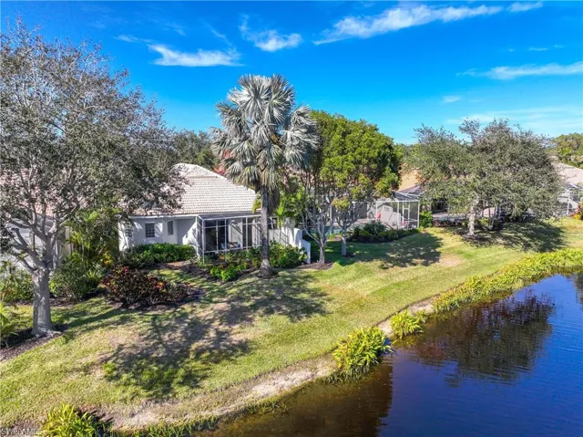 Rear view of house featuring a water view, a lanai, and a yard