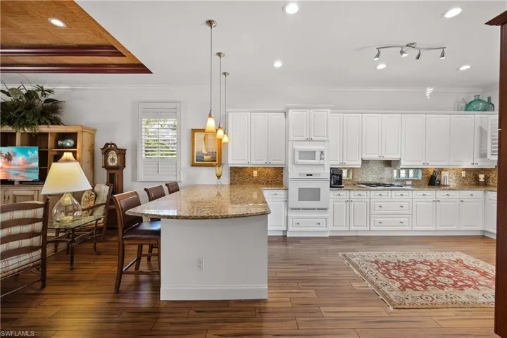Kitchen with pendant lighting, white appliances, a kitchen bar, and white cabinets