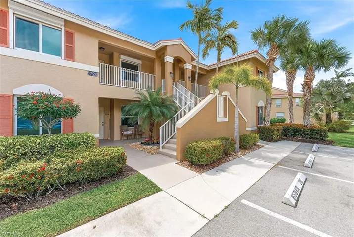 View of apartment building / complex with stairs and uncovered parking