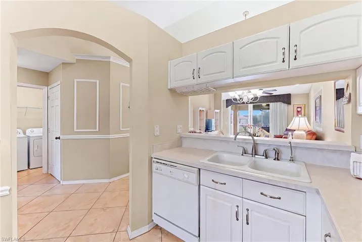 Kitchen featuring light countertops, white dishwasher, white cabinets, and washing machine and clothes dryer
