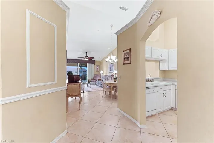 Hall with a chandelier, light tile patterned flooring, and crown molding