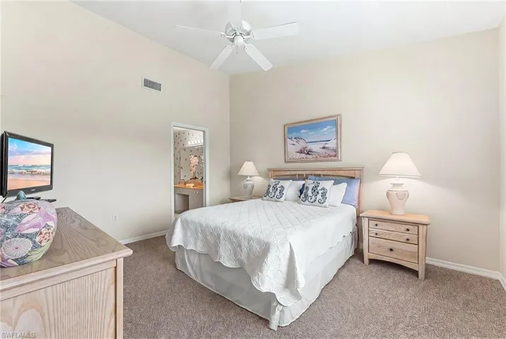 Carpeted bedroom with ceiling fan and connected bathroom