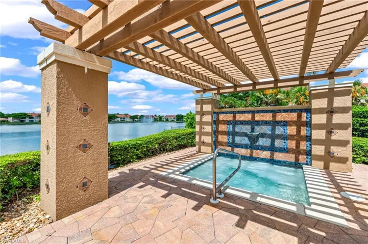 View of hot tub with a pergola, patio surround, a swimming pool, and a water view
