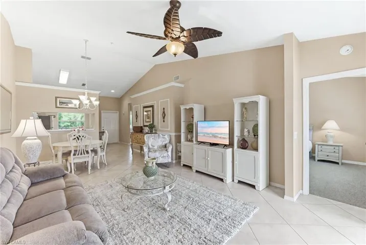 Living area featuring vaulted ceiling, a ceiling fan, light tile patterned flooring, and hanging lights