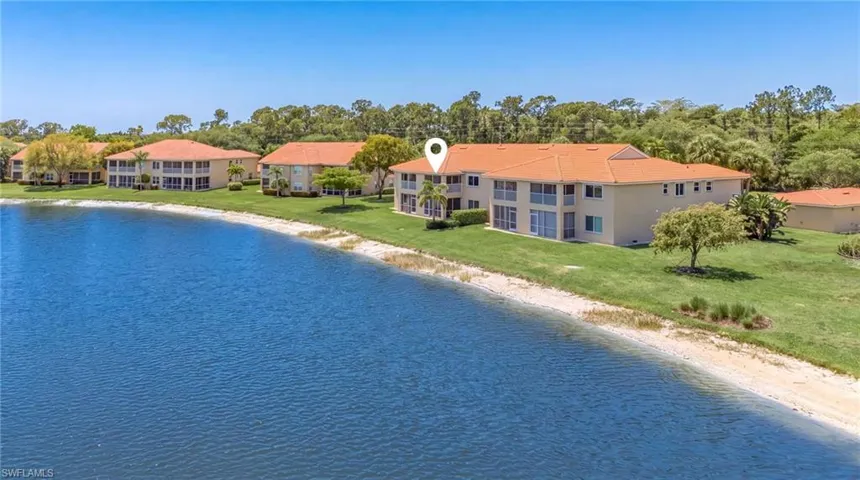 View of pool with view of water and beach, a lawn, and view of scattered trees