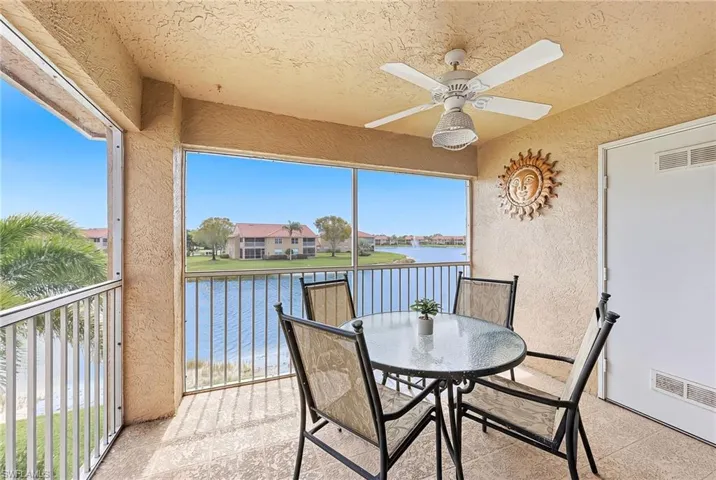Sunroom / solarium with a balcony, a ceiling fan, outdoor dining area, and a water view