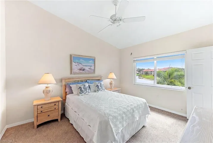 Bedroom featuring vaulted ceiling, light carpet, and a ceiling fan