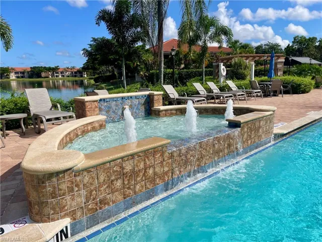 Community pool overlooking lake with a patio
