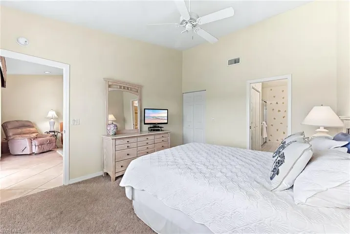 Bedroom with light colored carpet, a closet, a ceiling fan, a high ceiling, and light tile patterned floors