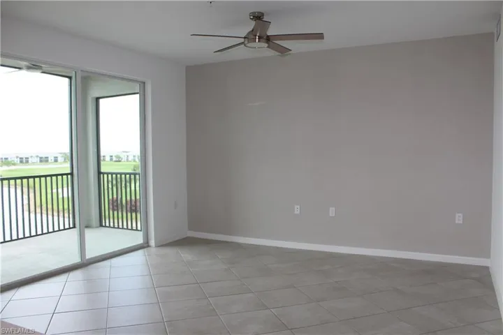 Unfurnished room with a ceiling fan, healthy amount of natural light, light tile patterned floors, and baseboards