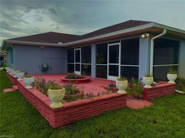 Rear view of house featuring a yard, a patio area, stucco siding, and a shingled roof