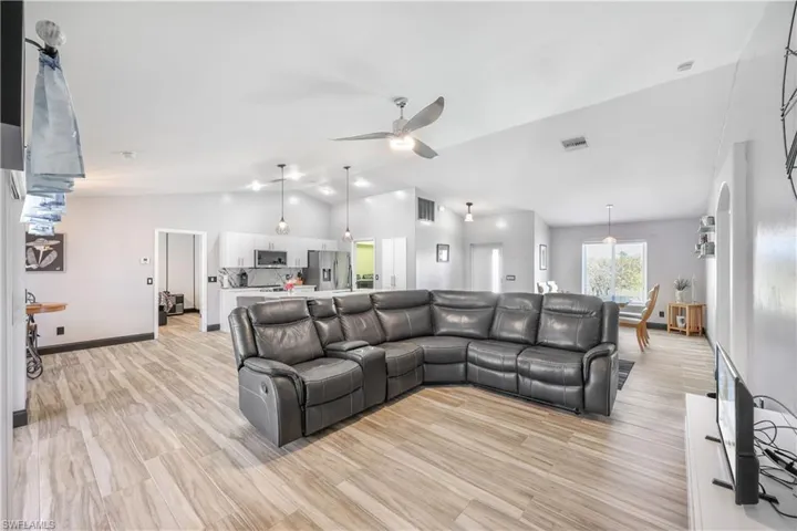 Living room featuring lofted ceiling, light wood-type flooring, and a ceiling fan