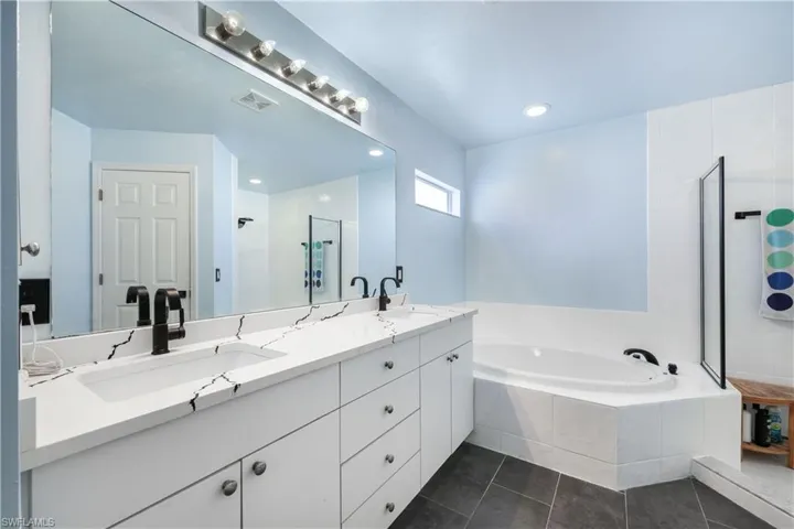 Bathroom with a garden tub, double vanity, dark tile patterned floors, recessed lighting, and walk in shower