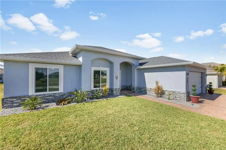 View of front of house featuring stone siding, a garage, stucco siding, and a front yard