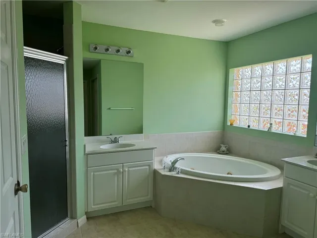 Bathroom featuring tile patterned flooring, separate shower and tub, and vanity