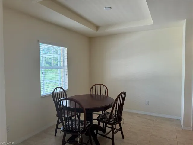 Tiled dining room featuring a raised ceiling