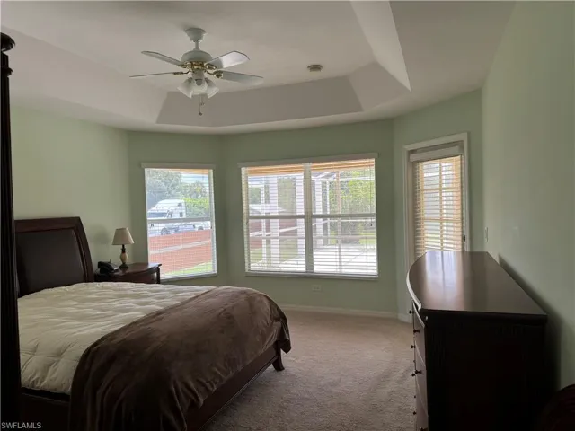 Bedroom featuring ceiling fan, carpet, and a tray ceiling