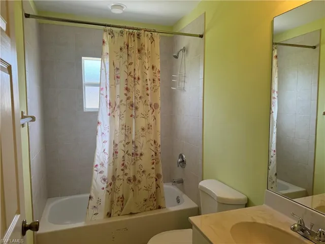 Full bathroom featuring vanity, shower / tub combo with curtain, and toilet