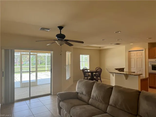 Living room with light tile patterned flooring, ceiling fan, and plenty of natural light