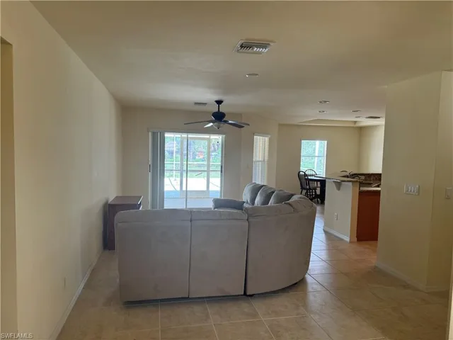 Living room with light tile patterned floors, a wealth of natural light, and ceiling fan
