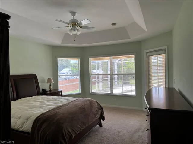 Bedroom featuring a raised ceiling, carpet, and ceiling fan