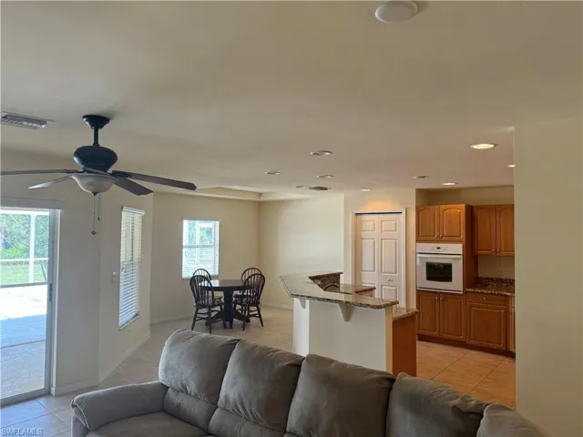 Tiled living room with a healthy amount of sunlight and ceiling fan