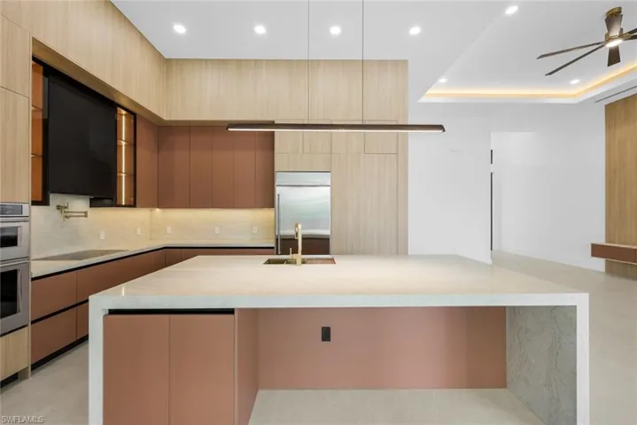 Kitchen with light wood finish cabinetry, light stone counters, stainless steel appliances, a spacious island, and recessed lighting