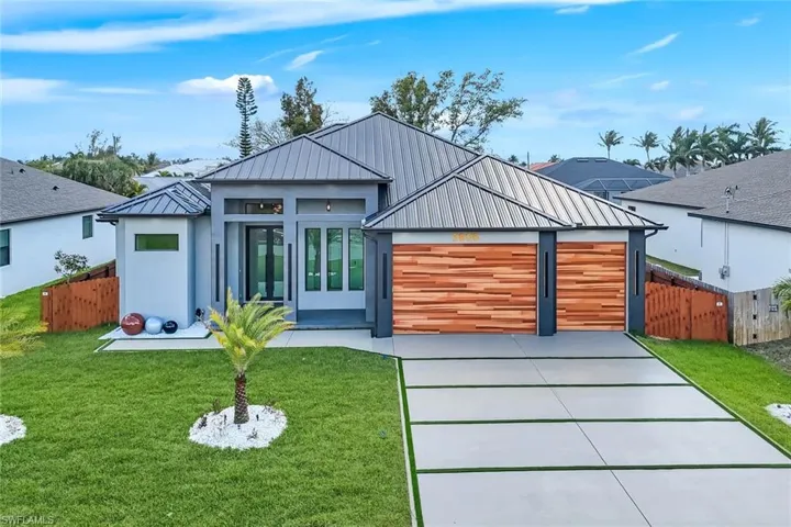 Contemporary house featuring a standing seam roof, concrete driveway, an attached garage, and stucco siding
