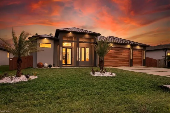 Prairie-style home with a garage, a standing seam roof, concrete driveway, and stucco siding