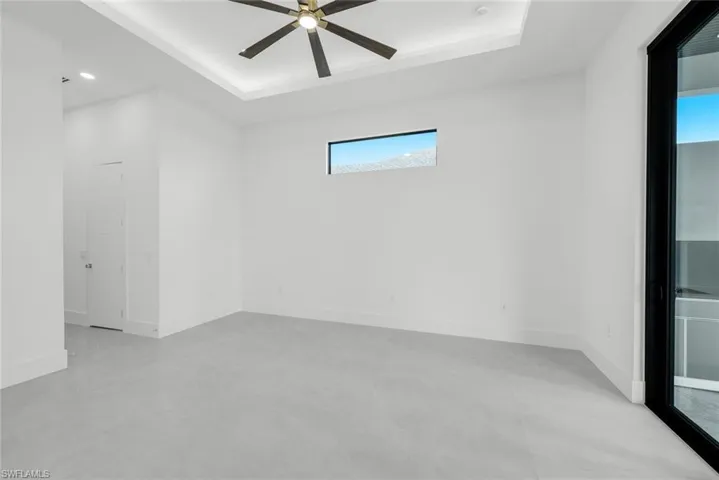 Empty room featuring concrete floors, a tray ceiling, and a ceiling fan