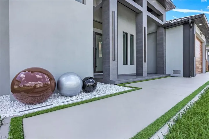 Property entrance featuring stucco siding, a standing seam roof, a patio, and a garage